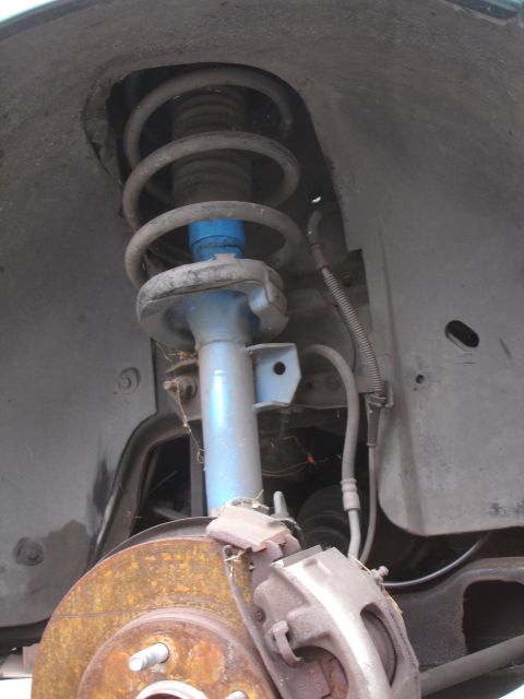 1993 Ford Taurus - Close-up view of a car's front suspension and brake system, showing a shock absorber and rotor.
