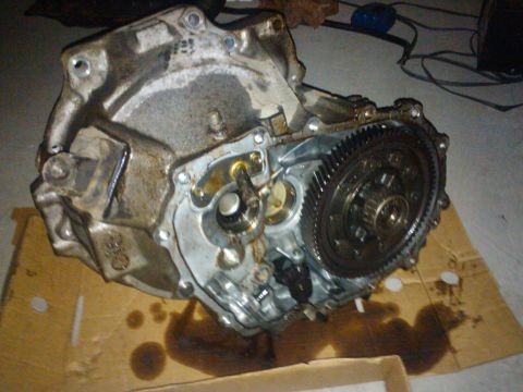 1993 Ford Probe - Transmission assembly with internal gears exposed, placed on cardboard for work.