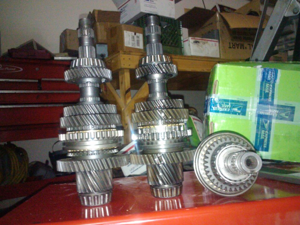 Two transmission gear sets and a bearing assembly on a red surface