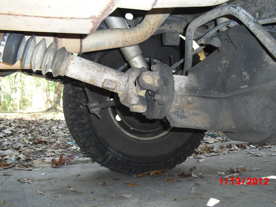Underside view of a vehicle's rear axle, driveshaft, and tire