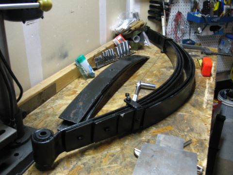 1995 Ford Bronco - Leaf springs and tools are laid out on a workbench, ready for installation.