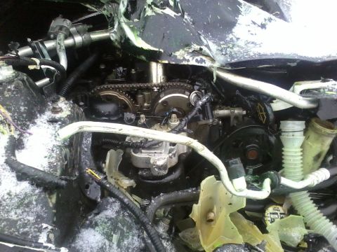 2006 Ford Fusion - Engine bay components visible after damage, with snow accumulation on parts.