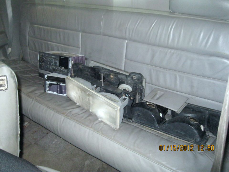 Gray leather bench seat with car headlights, stereo, and other parts