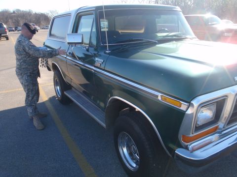 1978 Ford Bronco - Person in military uniform stands next to a green 1978 Ford Bronco in a parking lot.