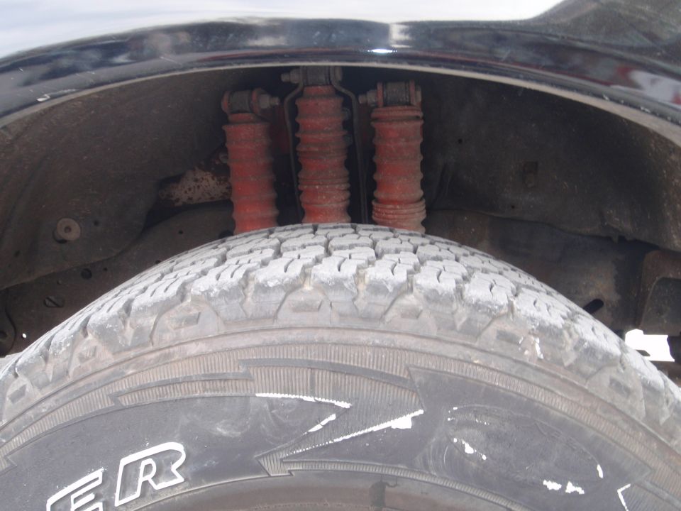 close-up of rear tire and red shock absorbers under wheel well