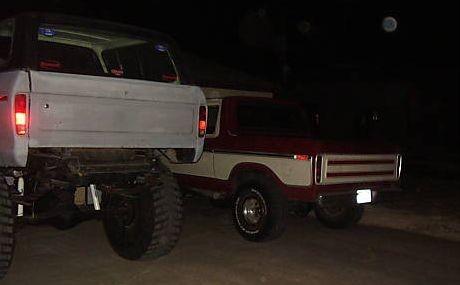 1978 Ford Bronco - Two Broncos are parked outside at night, with a full moon visible in the sky.