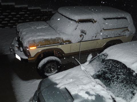 1978 Ford Bronco - A 1978 Ford Bronco sits covered in snow, parked beside another vehicle during a snowfall.