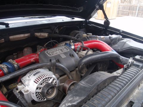 1994 Ford Bronco - Engine bay detail the "POWER STROKE TURBO 7.3L" engine component and red intake piping.