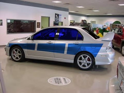 1997 Ford Taurus - Silver sedan with blue racing stripes and a large rear spoiler is parked indoors.