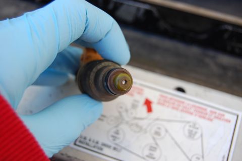 1994 Ford Bronco - A gloved hand holds a fuel injector, with a diagram visible in the background.