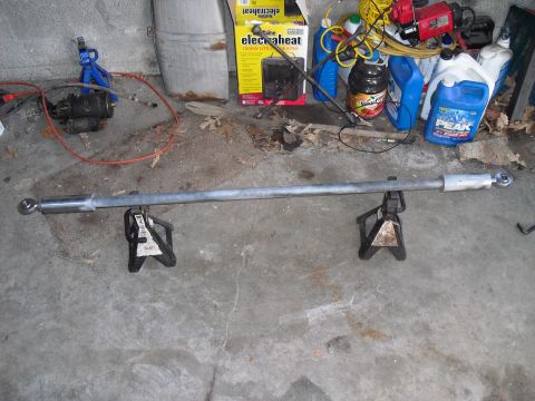 1986 Ford Bronco - A steering linkage assembly rests on two jack stands in a garage setting.
