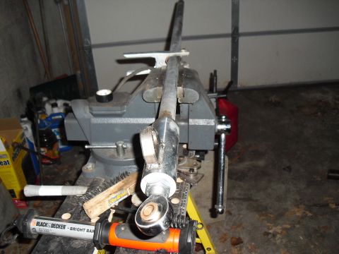1986 Ford Bronco - A metal rod assembly is secured in a vise, with tools and garage items in the background.