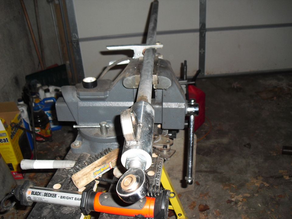 Metal rod assembly clamped in a vise with a brush and work light nearby
