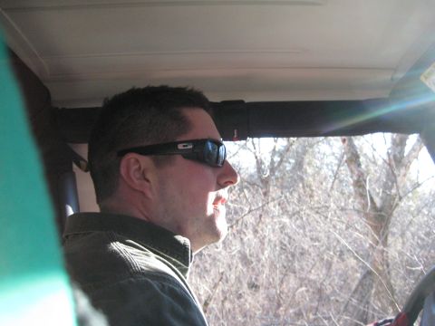 2005 Jeep Wrangler - A man drives a 2005 Jeep Wrangler through a wooded area on a sunny day.