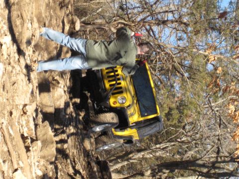 2005 Jeep Wrangler - A yellow Jeep Wrangler navigates a steep, rocky trail, with a person observing its progress.