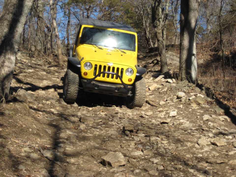 Yellow Jeep Wrangler climbing a rocky hill