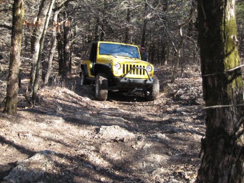 2005 Jeep Wrangler - A yellow 2005 Jeep Wrangler navigates a rocky, wooded trail.