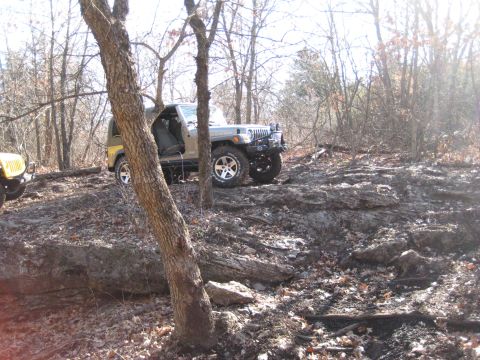 2005 Jeep Wrangler - A tan Jeep Wrangler navigates a rocky trail, with a yellow Jeep visible to the left.