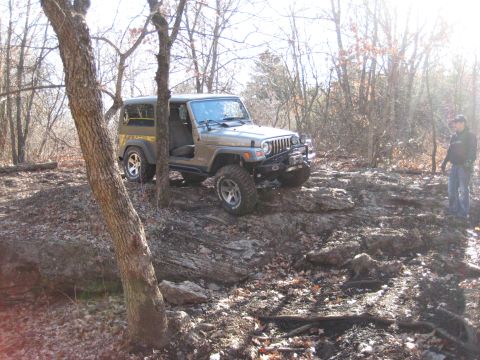 2005 Jeep Wrangler - A 2005 Jeep Wrangler navigates a rocky trail in a wooded environment.