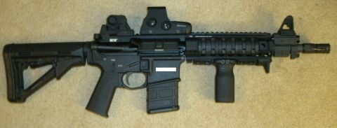 2000 Ford Crown Victoria - Assault rifle with multiple optical sights and a foregrip is displayed on a carpeted surface.
