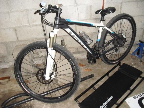 1986 Ford Bronco - A mountain bike is parked indoors, with its front wheel raised on a stand.