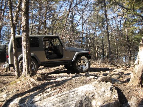 2005 Jeep Wrangler - A 2005 Jeep Wrangler navigates a challenging rocky path through a wooded area.