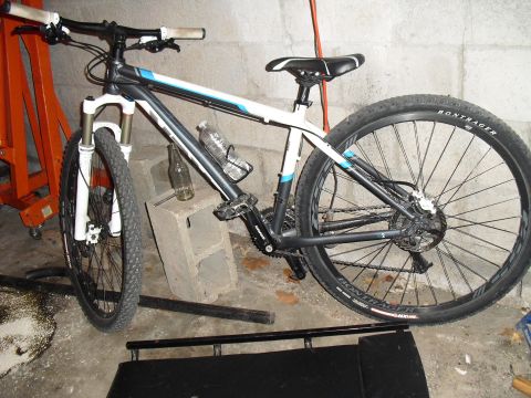 1986 Ford Bronco - A mountain bike is parked indoors next to a concrete block and an orange stand.