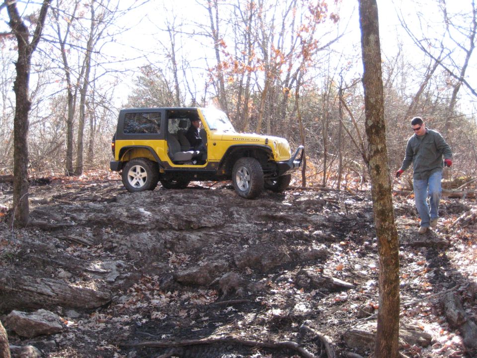 Yellow 2005 Jeep Wrangler on rocky trail with driver and passenger