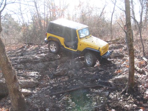 2005 Jeep Wrangler - This yellow 2005 Jeep Wrangler Rubicon navigates a challenging rocky terrain, demonstrating its off-road capabilities.