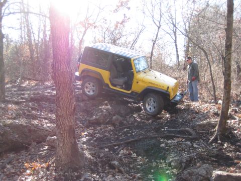 2005 Jeep Wrangler - Yellow 2005 Jeep Wrangler Rubicon navigating a challenging off-road trail in a wooded area.