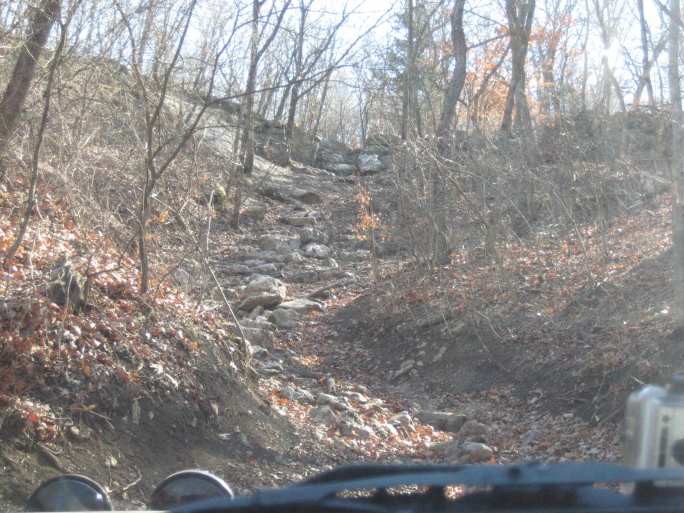 Jeep Wrangler dashboard and windshield view of a rocky, wooded trail