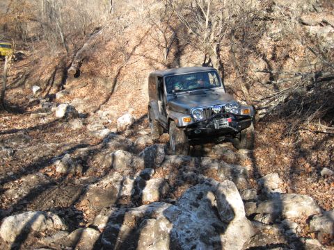 2005 Jeep Wrangler - A silver 2005 Jeep Wrangler tackles a challenging rocky off-road path, with another vehicle visible in the distance.