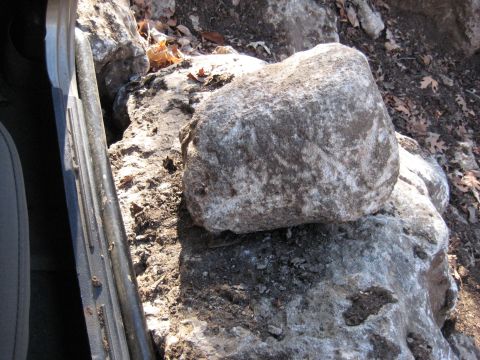 2005 Jeep Wrangler - A rock is placed on the door sill of a vehicle, surrounded by natural terrain.