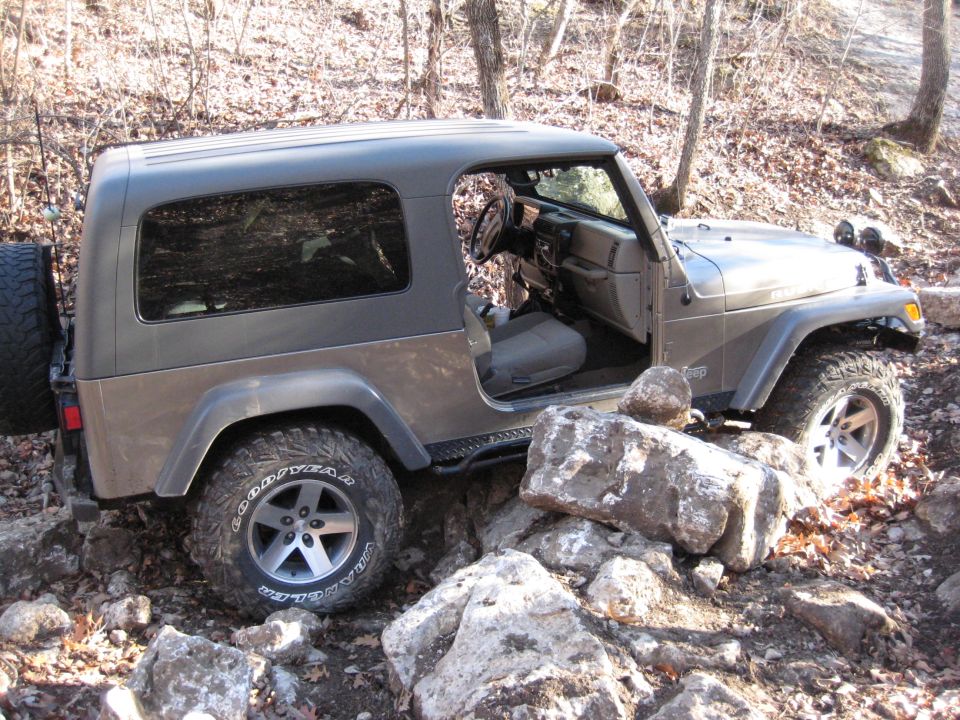 Brown Jeep Wrangler with a hardtop, off-roading over rocks