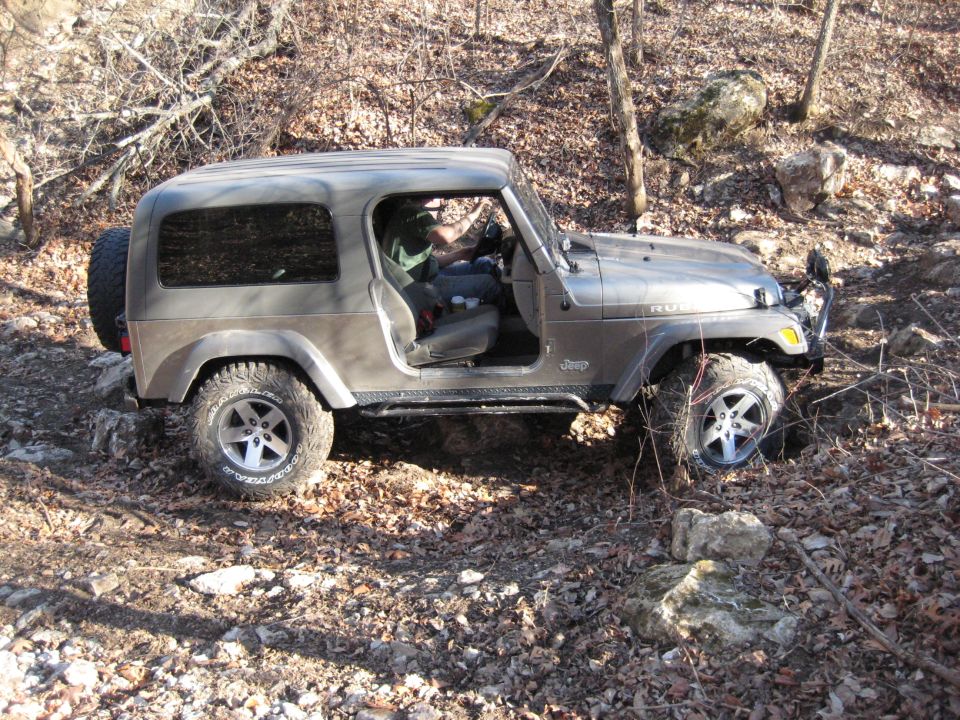 Gray 2005 Jeep Wrangler on a rocky trail with the driver's door open