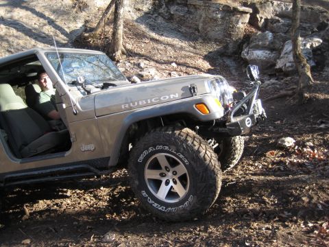 2005 Jeep Wrangler - A Jeep Wrangler Rubicon is shown off-roading on a dirt path with a rocky incline in the background.
