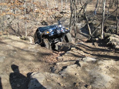 2005 Jeep Wrangler - A Jeep Wrangler navigates a rocky off-road course in a wooded area.