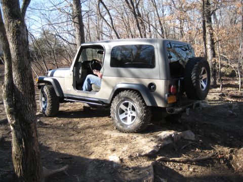 2005 Jeep Wrangler - A tan 2005 Jeep Wrangler navigates a rocky off-road path.