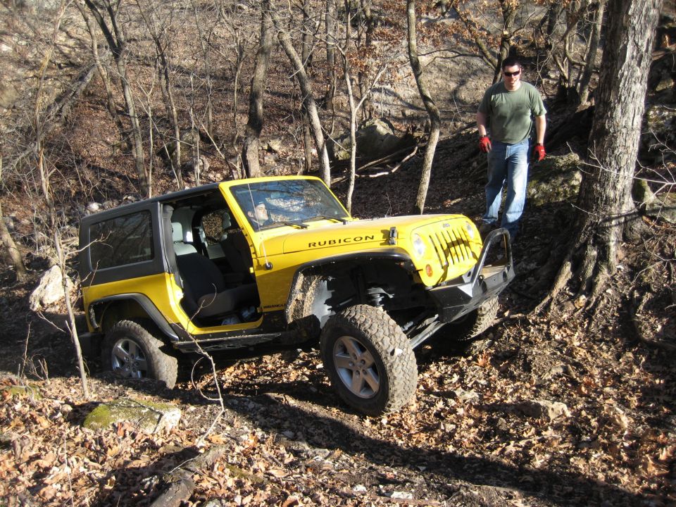 Yellow 2005 Jeep Wrangler Rubicon with doors removed, parked on a wooded trail
