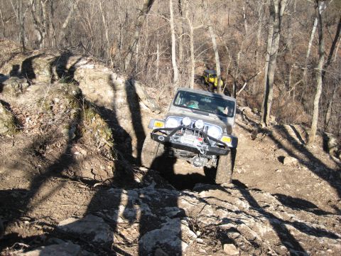 2005 Jeep Wrangler - A gray Jeep Wrangler navigates a challenging rocky incline, with another yellow vehicle visible further up the trail.