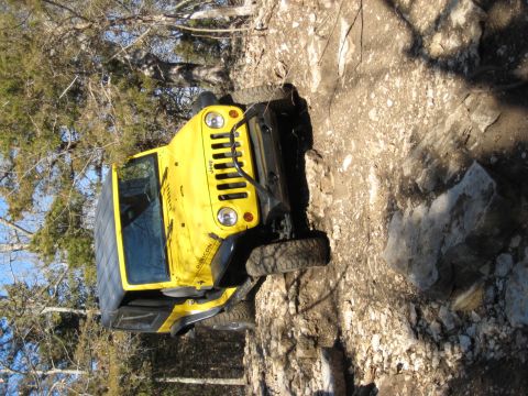 2005 Jeep Wrangler - A yellow Jeep Wrangler Rubicon navigates a rocky off-road path.