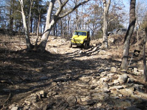 2005 Jeep Wrangler - Two Jeep Wranglers navigate a challenging rocky trail in a wooded area.