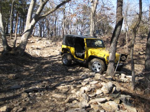 2005 Jeep Wrangler - A yellow 2005 Jeep Wrangler Rubicon tackles a challenging rocky terrain on an off-road trail.