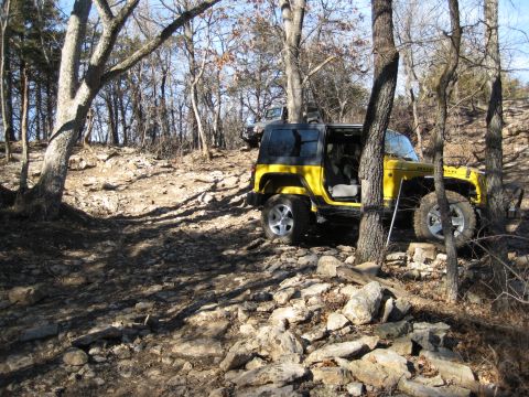 2005 Jeep Wrangler - Yellow Jeep Wrangler on a rocky trail, with another Jeep visible behind it.