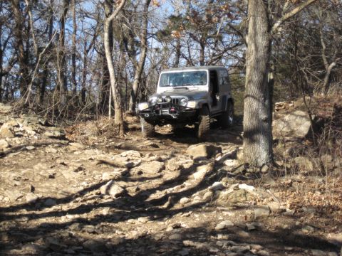 2005 Jeep Wrangler - Silver 2005 Jeep Wrangler navigates a challenging rocky path through a forest.