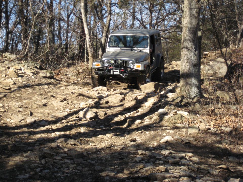 Silver 2005 Jeep Wrangler driving on a rocky trail