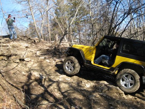 2005 Jeep Wrangler - A yellow 2005 Jeep Wrangler Rubicon navigates a challenging rocky terrain on an off-road trail.