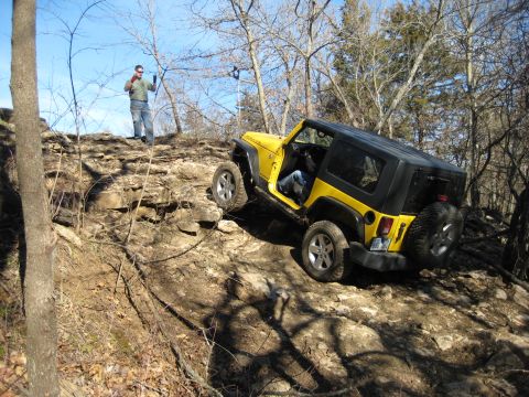 2005 Jeep Wrangler - A yellow 2005 Jeep Wrangler tackles a challenging rocky terrain, demonstrating its off-road capabilities.
