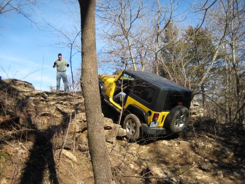 2005 Jeep Wrangler - A yellow Jeep Wrangler maneuvers through a challenging rocky off-road course with a man observing from above.