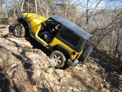 2005 Jeep Wrangler - A yellow Jeep Wrangler navigates a rocky trail, demonstrating its off-road capabilities.